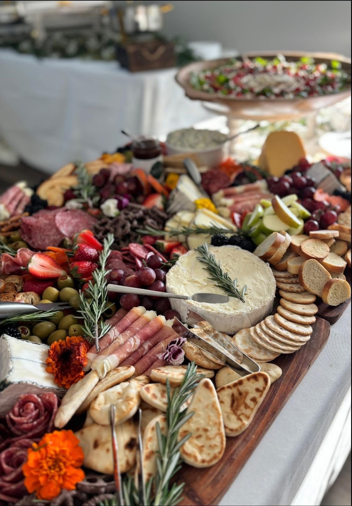Abundant grazing board with brie, charcuterie, fruit and rosemary